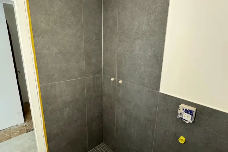Bodengleiche Dusche mit großformatigen grauen Platten kurz vor der Fertigstellung