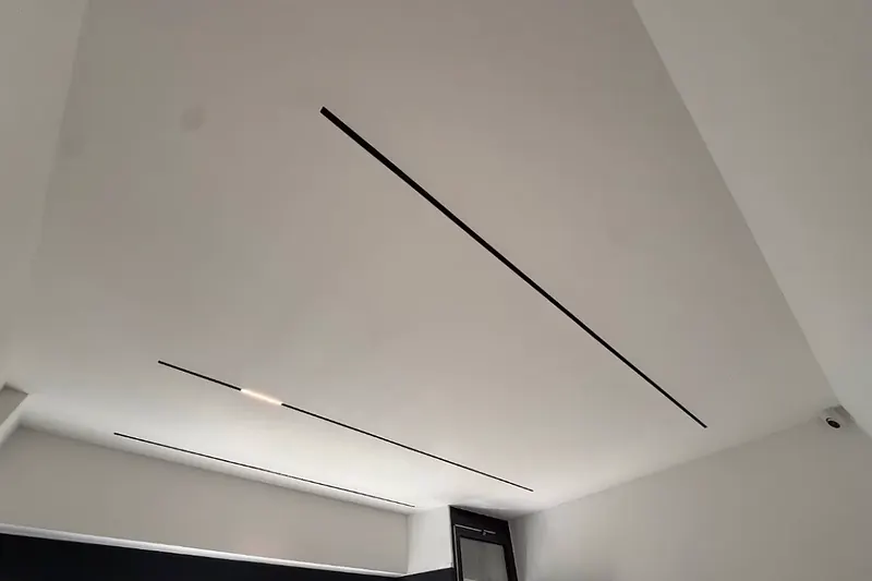 Fertige weiße Decke mit zwei eingelassenen schwarzen Lichtbändern, Leuchten in Betrieb