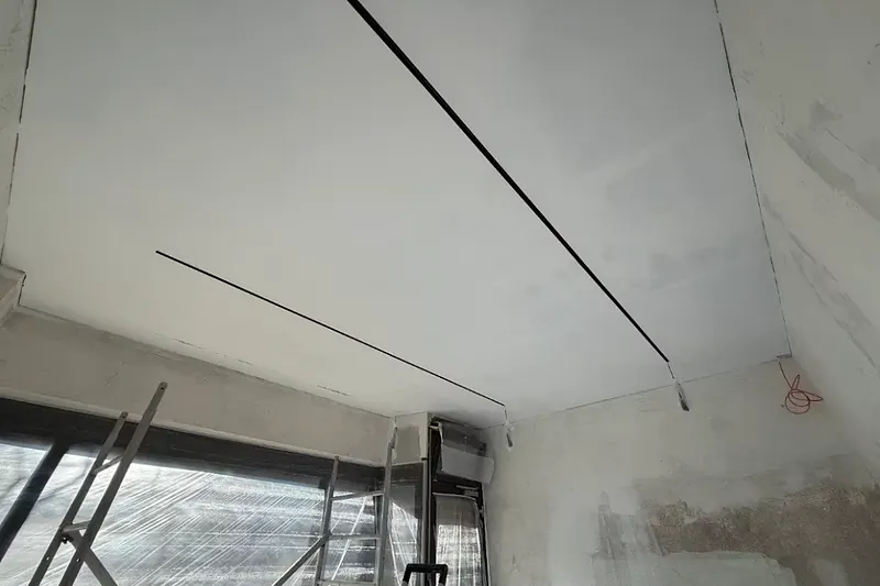 Abgehängte Decke während der Bauphase, Rohputz an den Wänden und offene Kabel