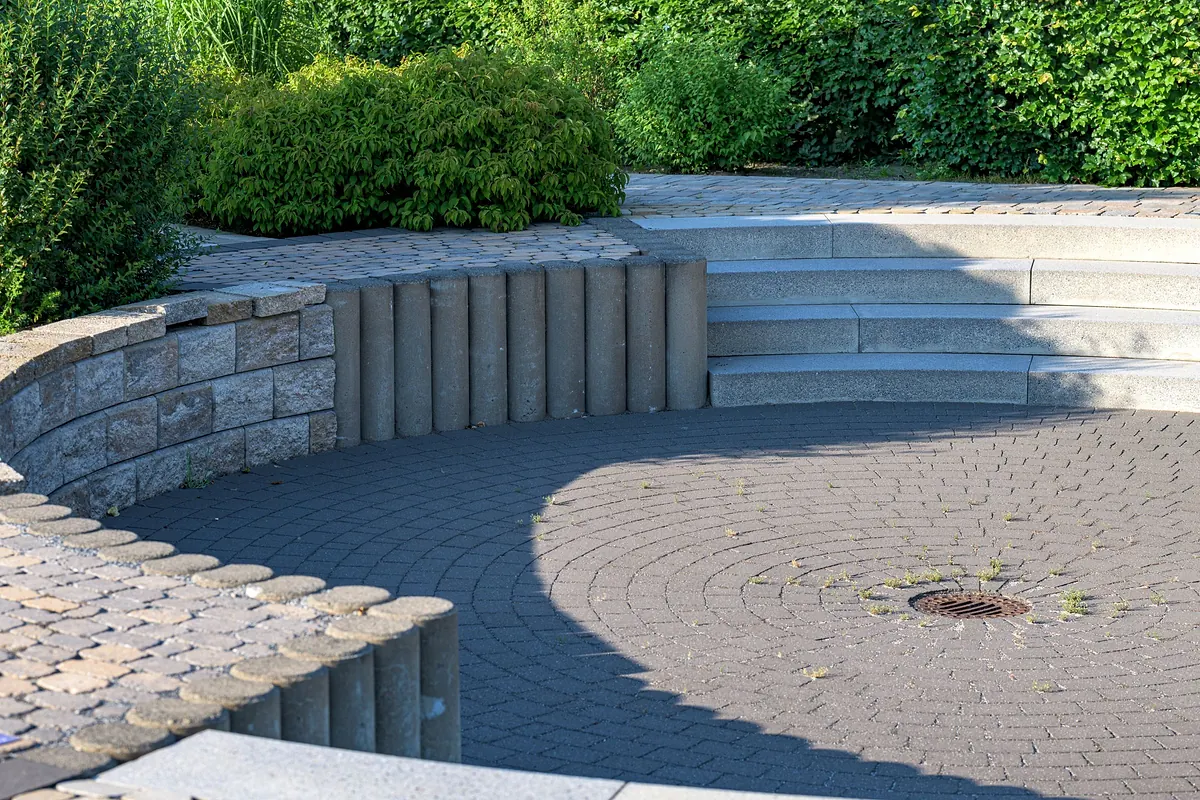 Gepflasterte Terrasse mit Natursteinmauer, Stufen und Hecke