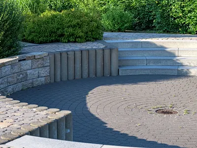 Gepflasterte Terrasse mit Natursteinmauer, Stufen und Hecke