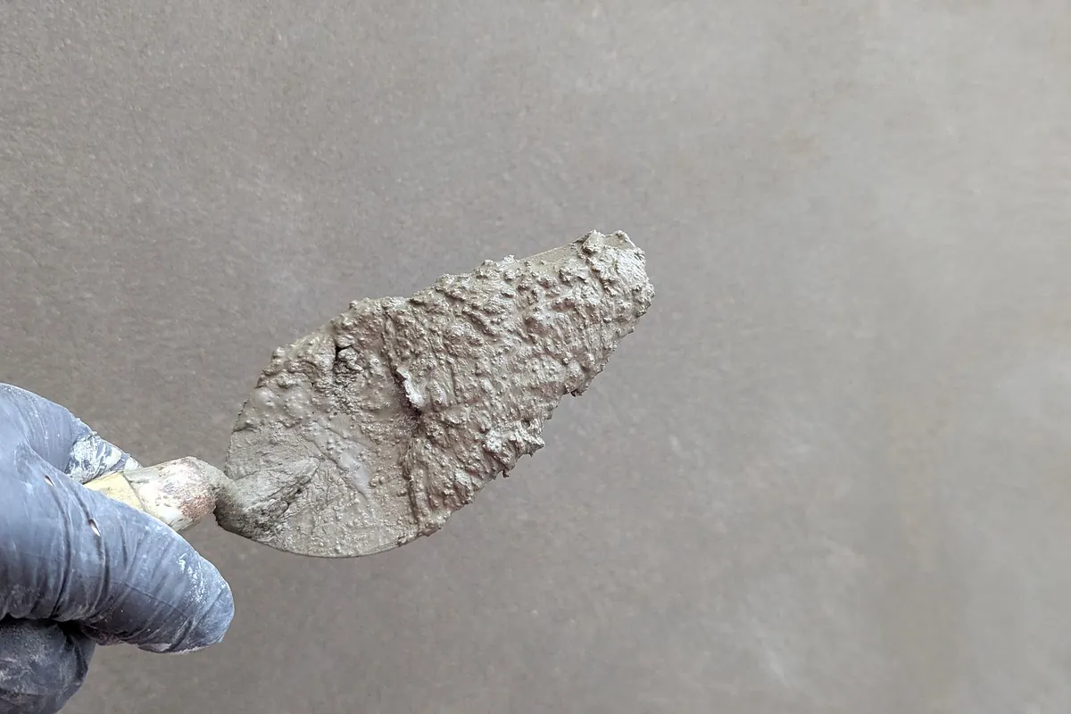 Kelle mit frischem Putz vor einer glatt gezogenen Wand