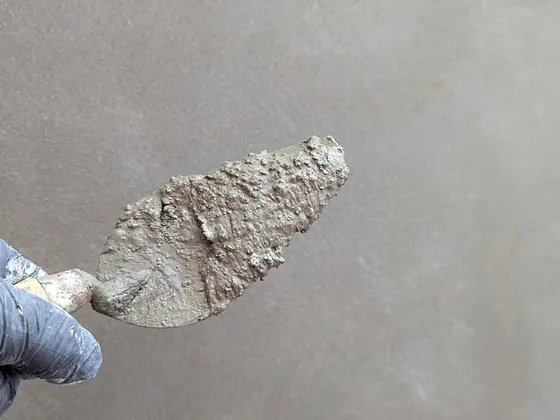Kelle mit frischem Putz vor einer glatt gezogenen Wand