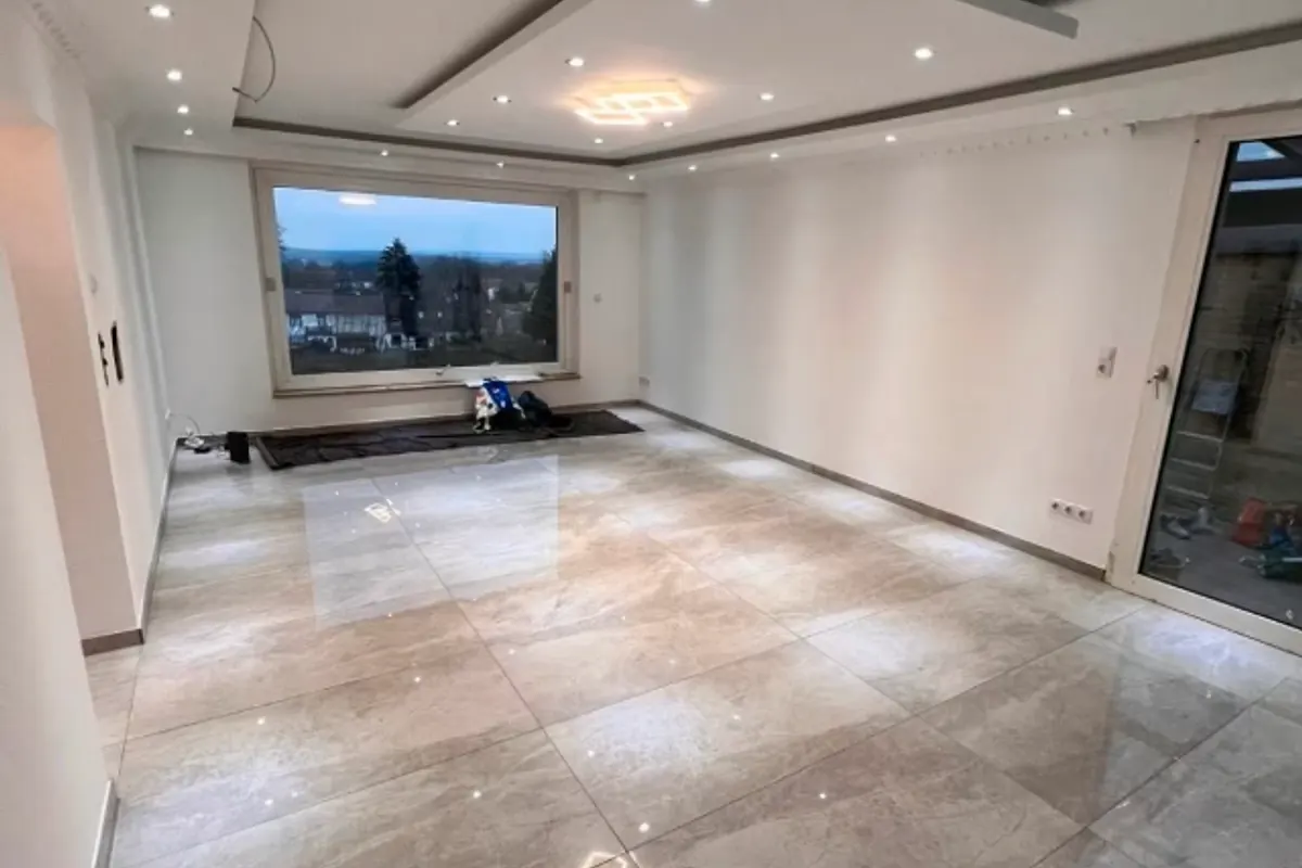 Wohnraum mit großformatigem Bodenbelag und abgehängter Lichtdecke